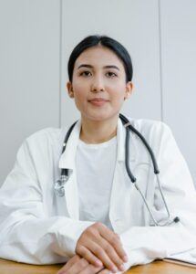 A female doctor confidently sits at her desk, ready for consultation in a medical office.